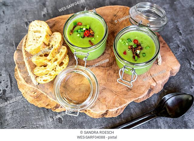 Two glasses of pea soup with fried tofu, red chili pepper and spring onions