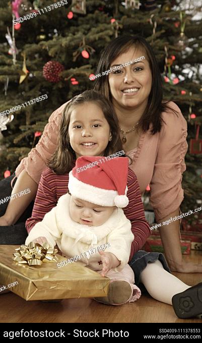 Hispanic mother and children in front of Christmas tree