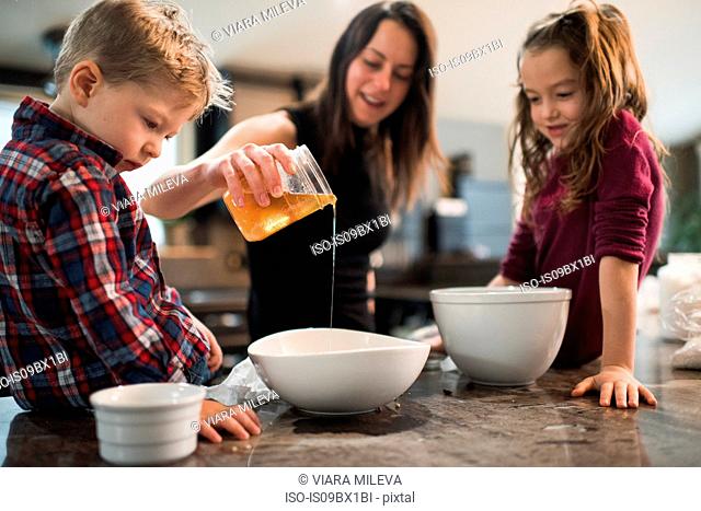 Children watching mother pour honey into bowl