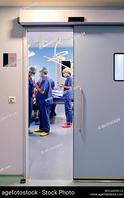 Doctors wearing face mask having discussion while standing in operation room at hospital