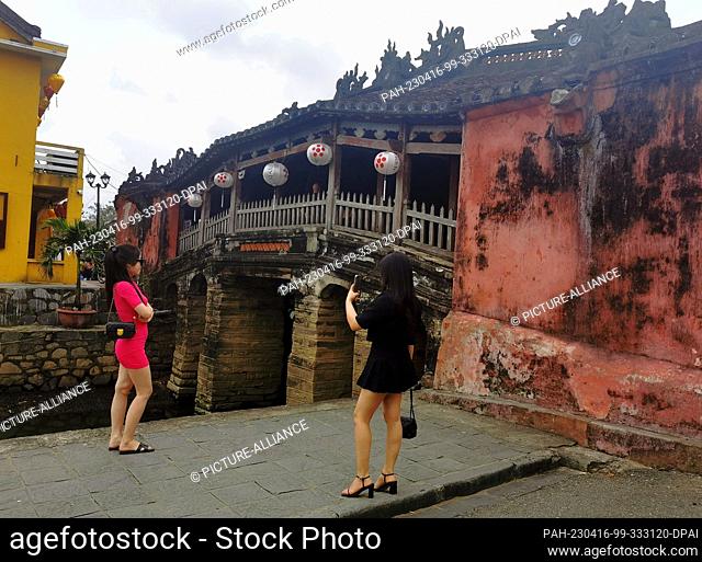 02 March 2023, Vietnam, Hoi An: Two women take a picture of themselves in front of Chua Cau Bridge (also Japanese Bridge