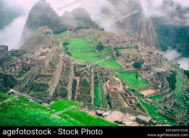 Classic view of the ancient mysterious city of Machu Picchu with intense clouds on the background in Peru. Astonishing wallpaper image