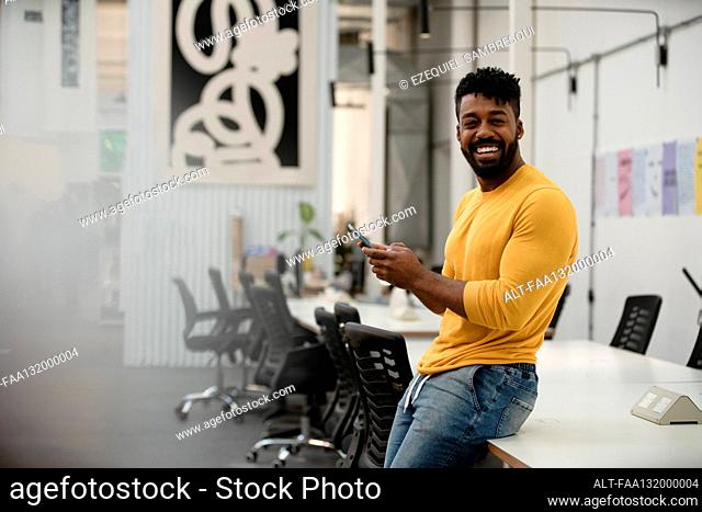 African American man holding smart phone while looking at the camera