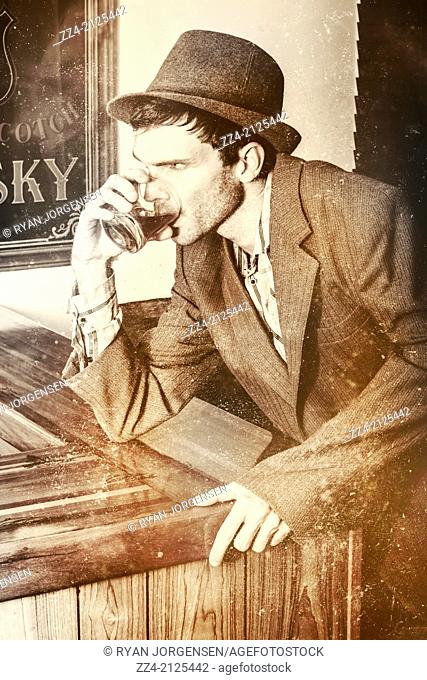 Faded and weathered turn of the 19th century photo of a Wild West American outlaw drinking Irish whiskey drink with serious expression while getting gun trigger...