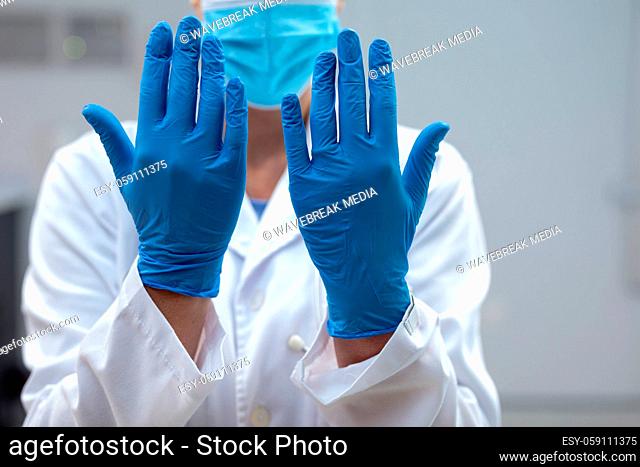 Midsection of caucasian female doctor wearing mask and latex gloves