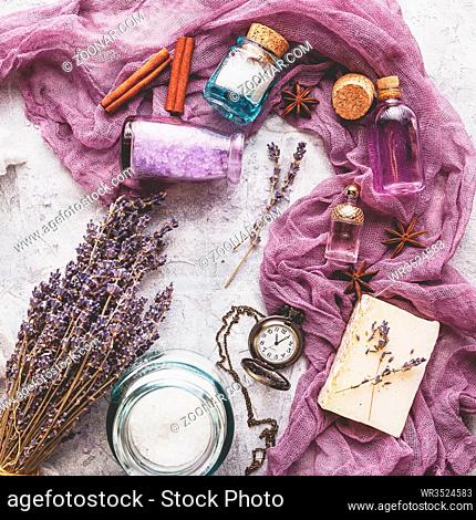Lavender background with bouquet and twigs of dry lavender, bottle with cosmetic oil, perfume bottle, soap, vintage pocket watch, cinnamon sticks
