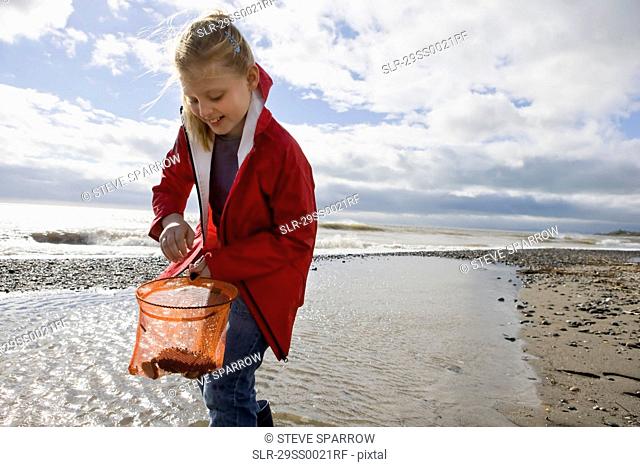 Young girl looking into fishnet at beach