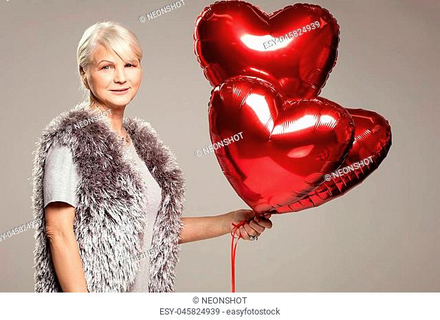 Elegant adult woman holding red balloons, valentine's day