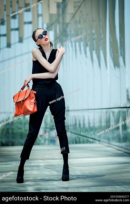 Beautiful young Asian business woman with leather bag around a glass office building