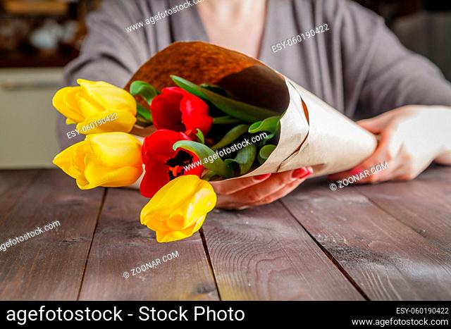 Woman holding in hands tulips in craft paper