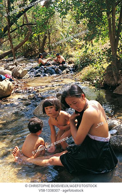 WOMAN AND CHILDREN BATHING IN THE HOT SPRINGS, PAI REGION, THAILAND
