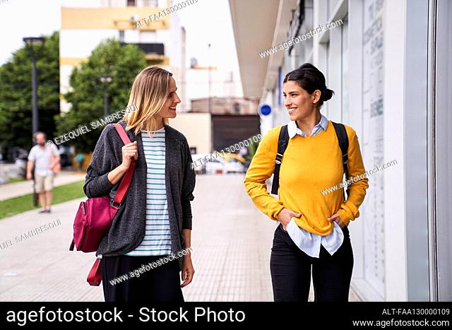 Two happy women going for a walk and window shopping