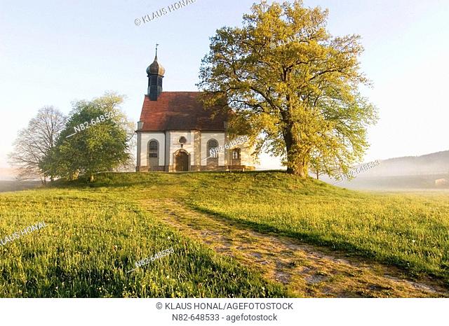 Small chapel on hill at foggy morning in spring. Franconia, Bavaria / Germany