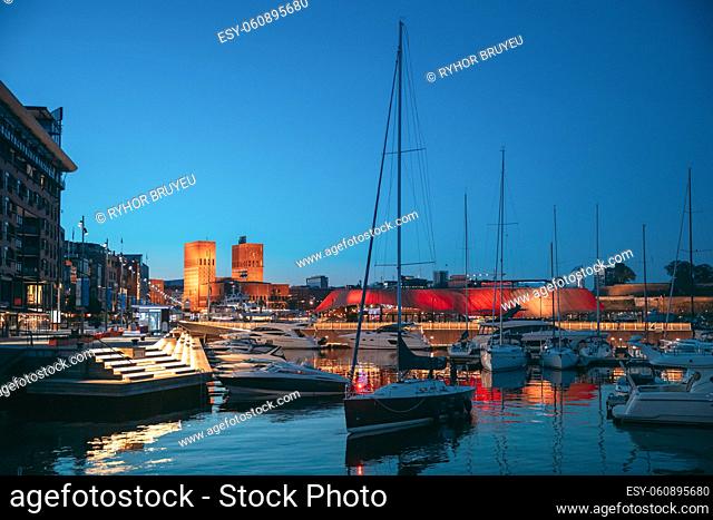 Oslo, Norway. Night View Embankment, Oslo City Hall And Moored Yachts Near Aker Brygge District. Summer Evening. Famous And Popular Place