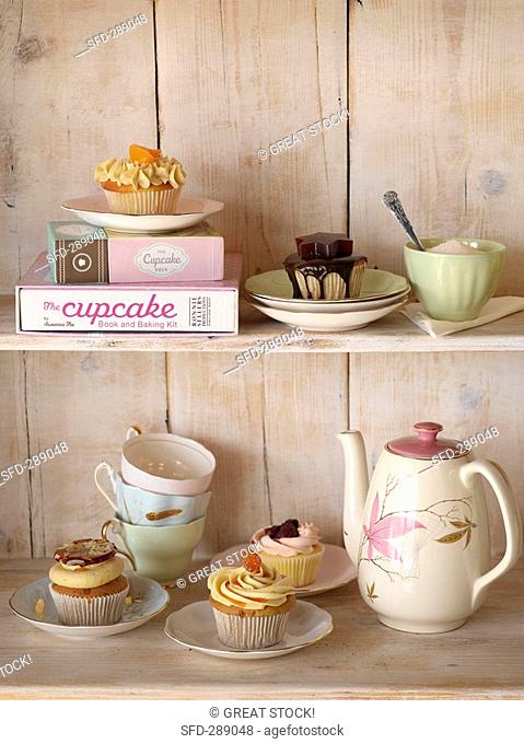 Cupcakes and tea things on wooden shelves