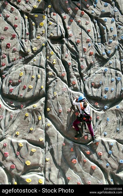girl climbs a big rock wall at the gym