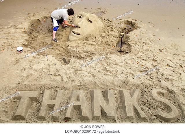 England, London, Waterloo, An artist sculpting a head in sand with the word 'THANKS' below, on the South Bank embankment near Waterloo in London