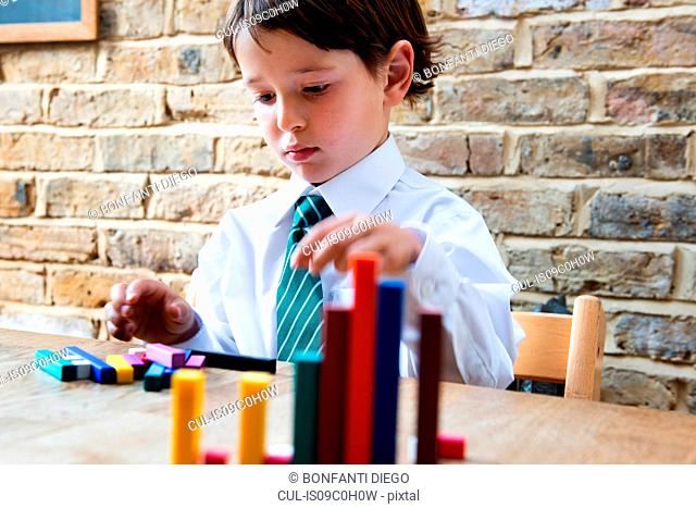 Boy in school uniform playing with colour sticks at home