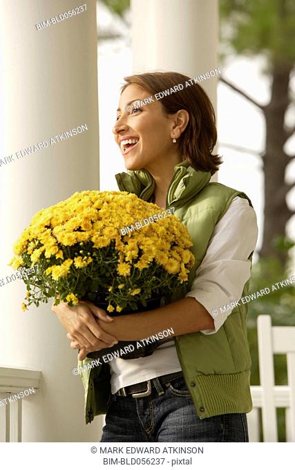 Hispanic woman carrying potted plant