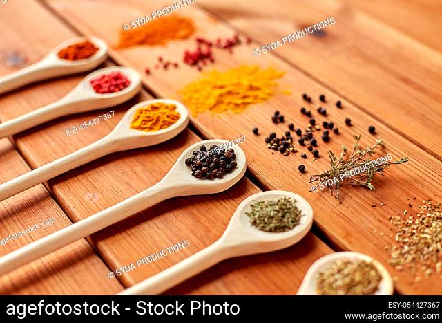 spoons with different spices on wooden table