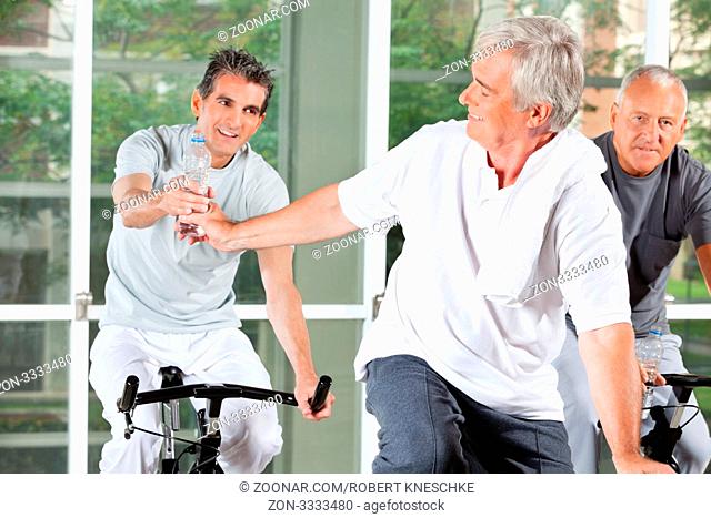 Ältere Männer auf Spinning-Rädern mit Wasser im Fitnesscenter