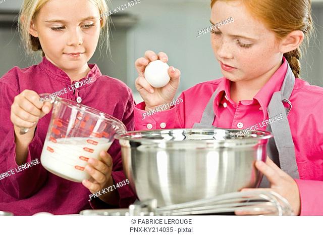 Two girls cooking food in the kitchen