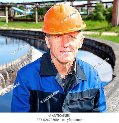 Portrait of Caucasian senior manual worker sitting near water filtration unit