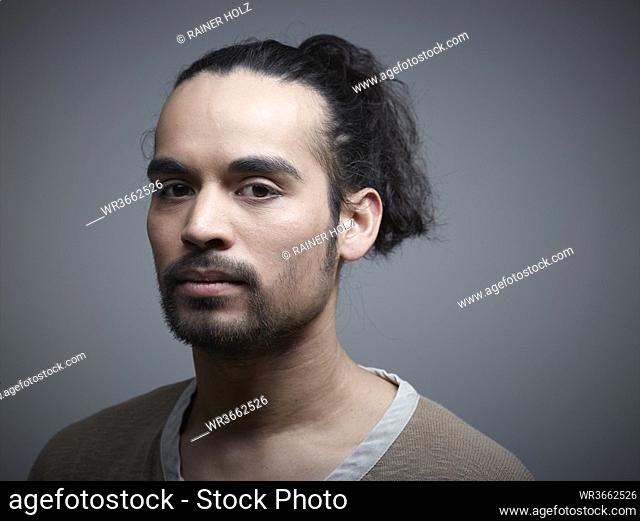Portrait of young man against grey background, close up