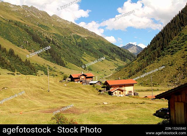 swiss alp stable on farm land with hut and blue sky