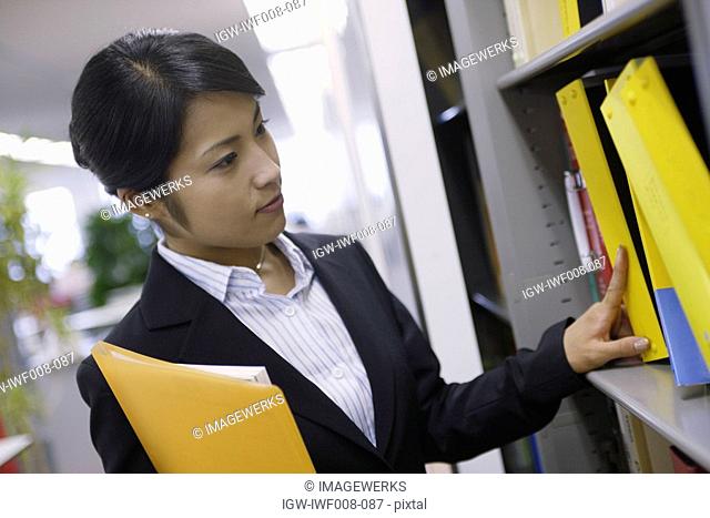 A woman looks over the shelf containing various files
