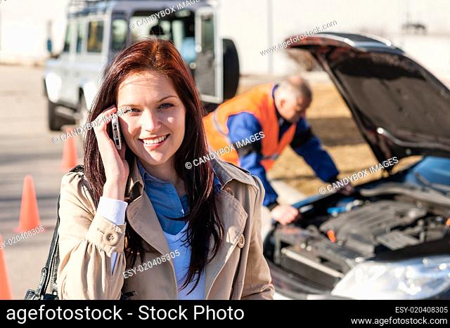 Woman talking on cellphone after car breakdown