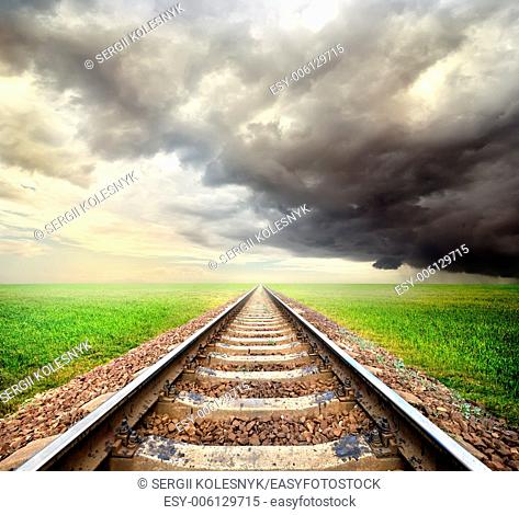 Railway in the field and storm clouds