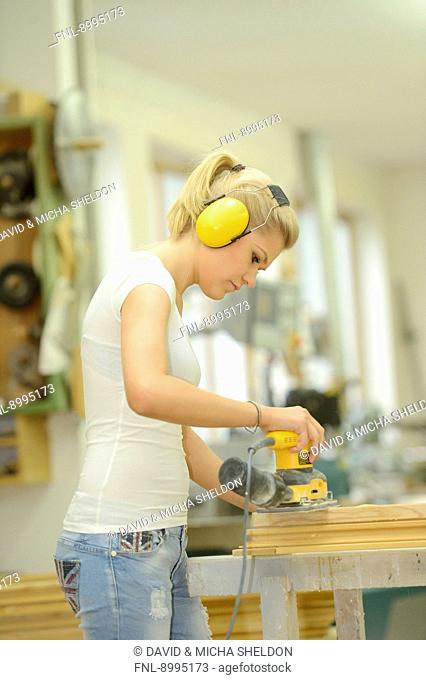 Young woman in a carpentry working on a window frame