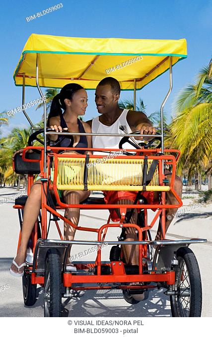 Multi-ethnic couple riding in pedal cart