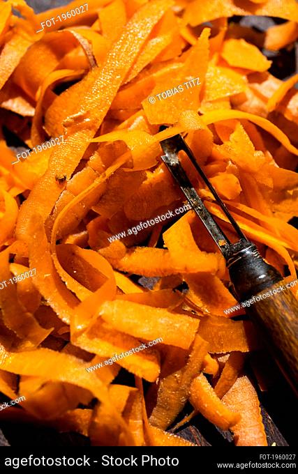 Close up vibrant orange carrot strips and peeler