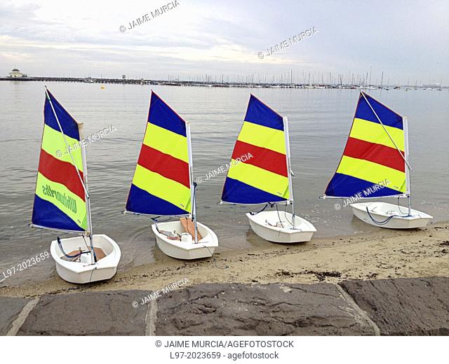 Four small sail boats with multi coloured sails sitting on St Kilda beach, Melbourne Australia