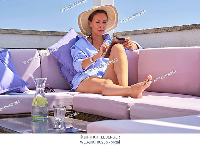 Woman with tablet relaxing on sun deck