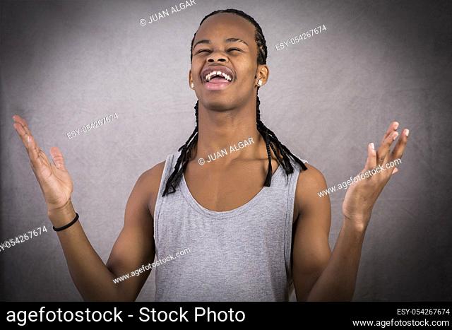 Cheerful confused young black man posing on gray background in studio