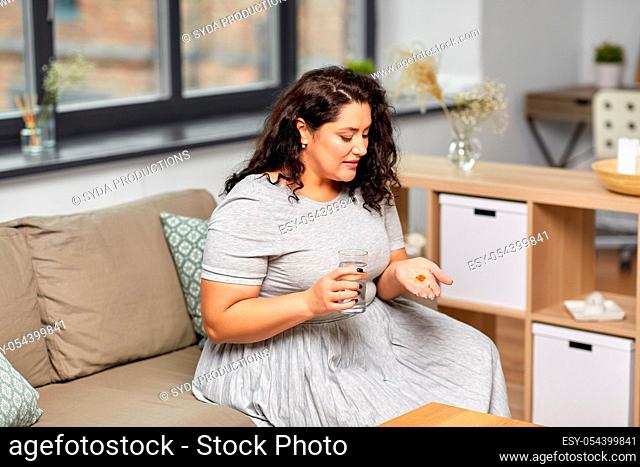 woman with cod liver oil pills and water at home