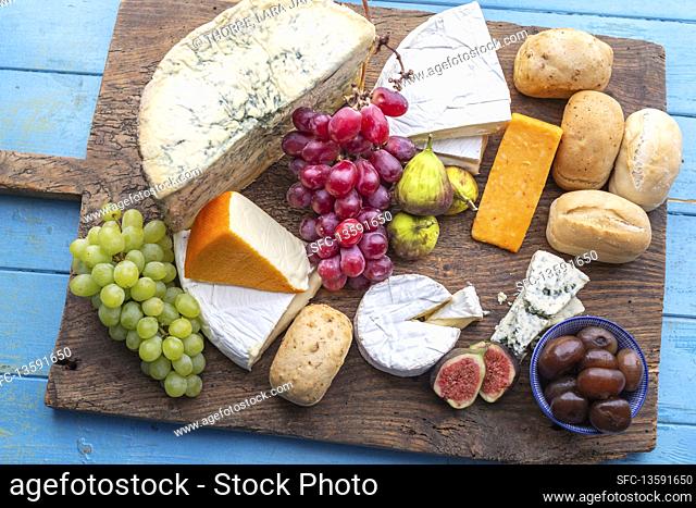 Cheese board with buns, figs, grapes and pickled onions