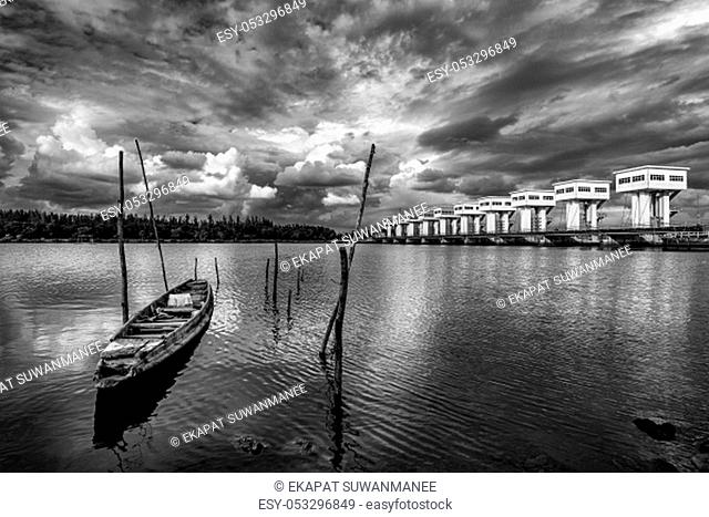 Fishing boat and water barrier and river with cloud sky storm in rain season, Black and white and monochrome style