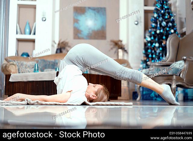 Beautiful Woman Lays On Her Back With Legs Stretching Above Her Head. Mature Woman Actively Practices Yoga. Stretching Spine. Workout