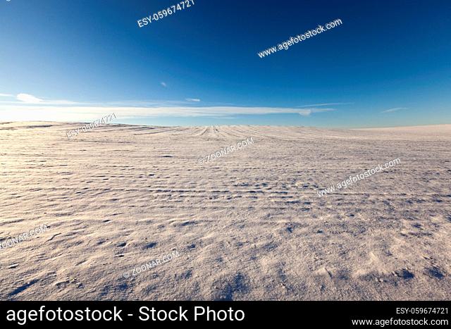 white snow on a plowed field in the winter season. photo with blue sky