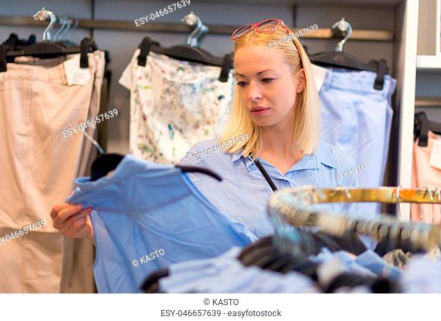 Beautiful woman shopping fashionable clothes in clothing store