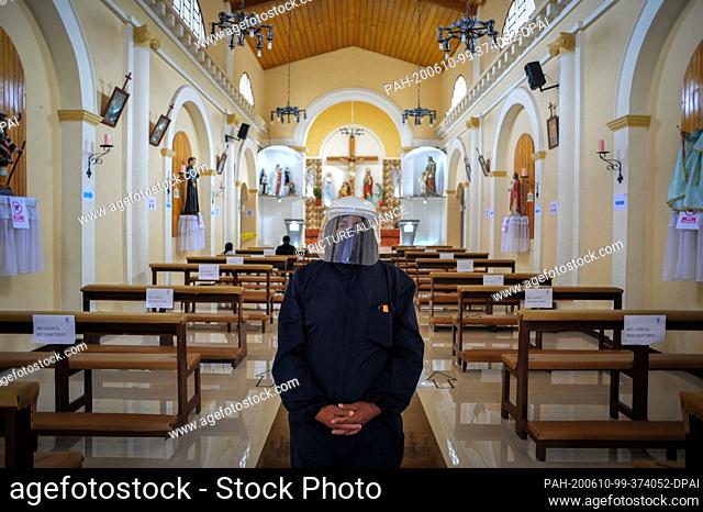 09 June 2020, Ecuador, Quito: A volunteer in a protective suit is waiting at the entrance of the church of Lloa, south of Quito