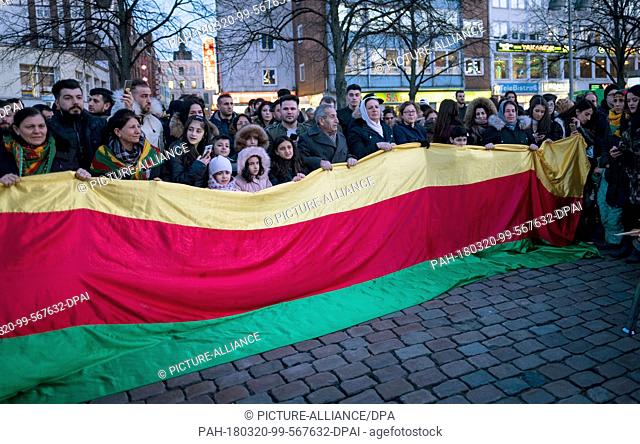 20 March 2018, Germany, Hanover: Kurdistan's flag is collectively held by several people during the ignition of the traditional Nowruz fire