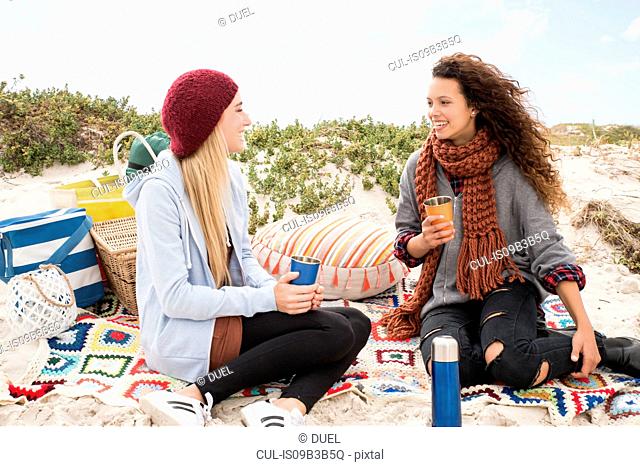 Two young women chatting beach picnic, Western Cape, South Africa