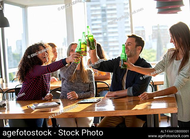 Smiling business people toasting bottles in office