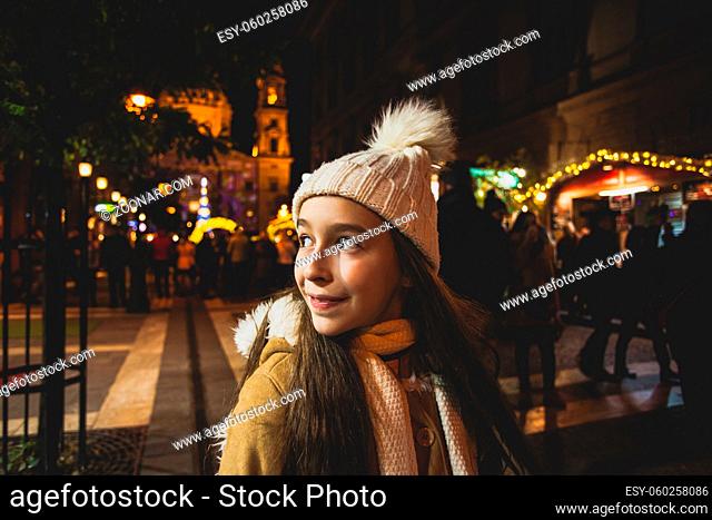 Beautiful little girl makes a wishes at new years night at Christmas market. Winter family vacations