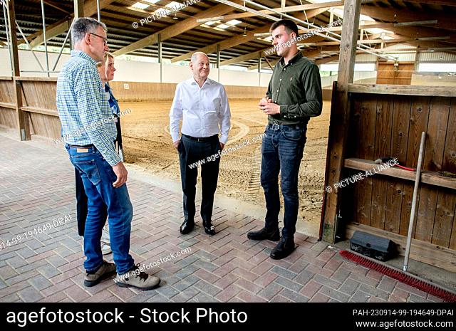 14 September 2023, Bremen: Chancellor Olaf Scholz (M, SPD) visits an indoor riding arena on the organic farm together with farmer Max Sündermann (r) and parents...